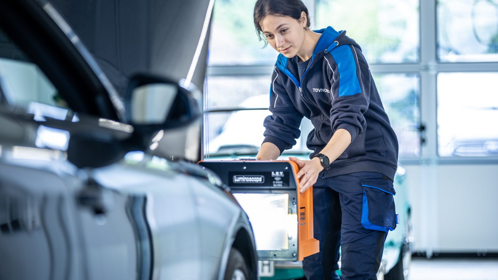 Prüferin von TÜV NORD führt einen Lichtcheck an einem Fahrzeug durch