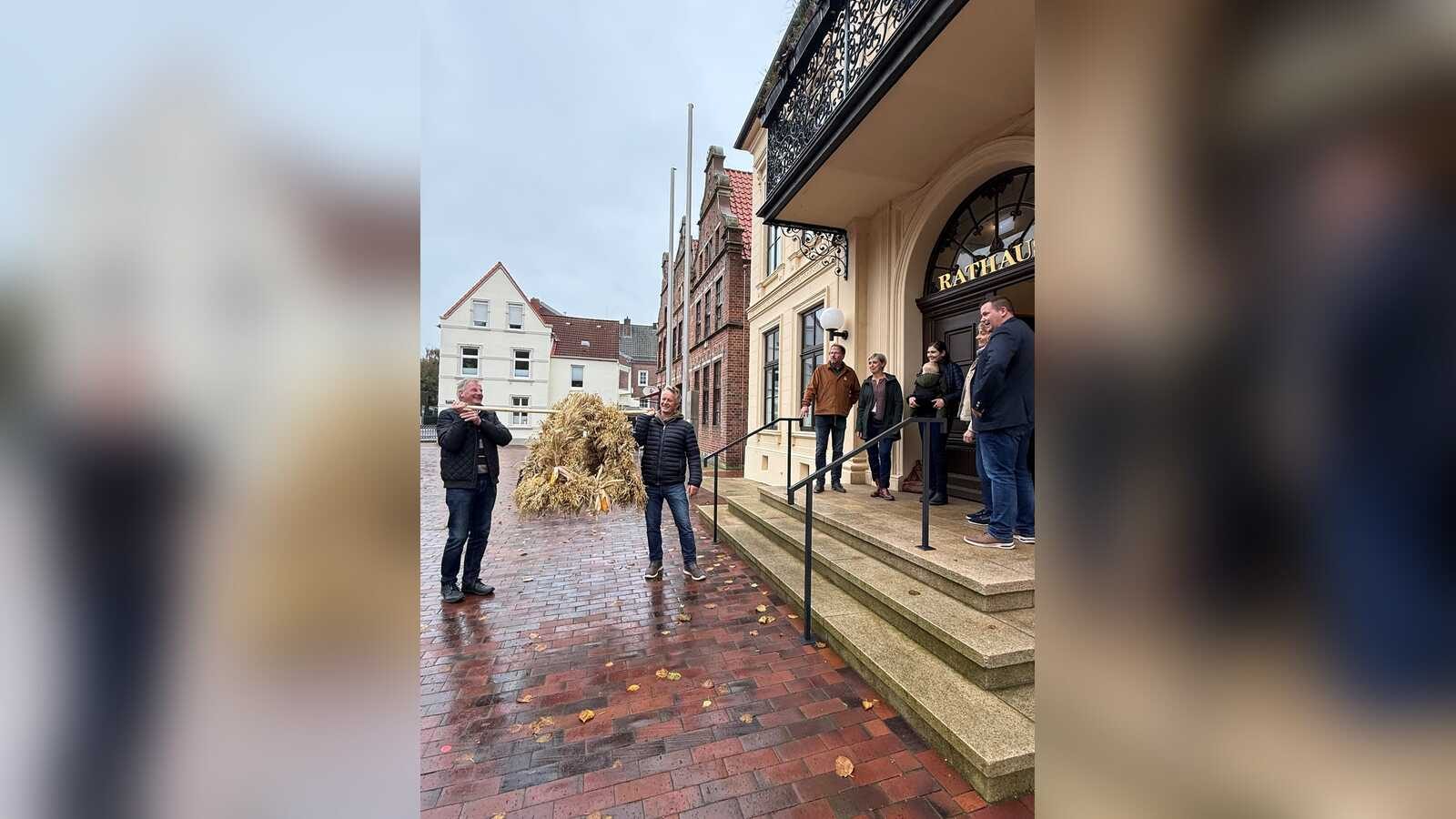 Vertreterinnen und Vertreter von Landvolk und Küstenfrauen übergeben Bürgermeister Florian Eiben die Erntekrone vor dem Rathaus Norden