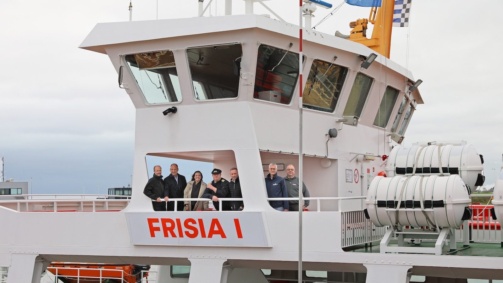 Sieben Personen stehen auf der Brückennock der weißen Inselfähre Frisia I