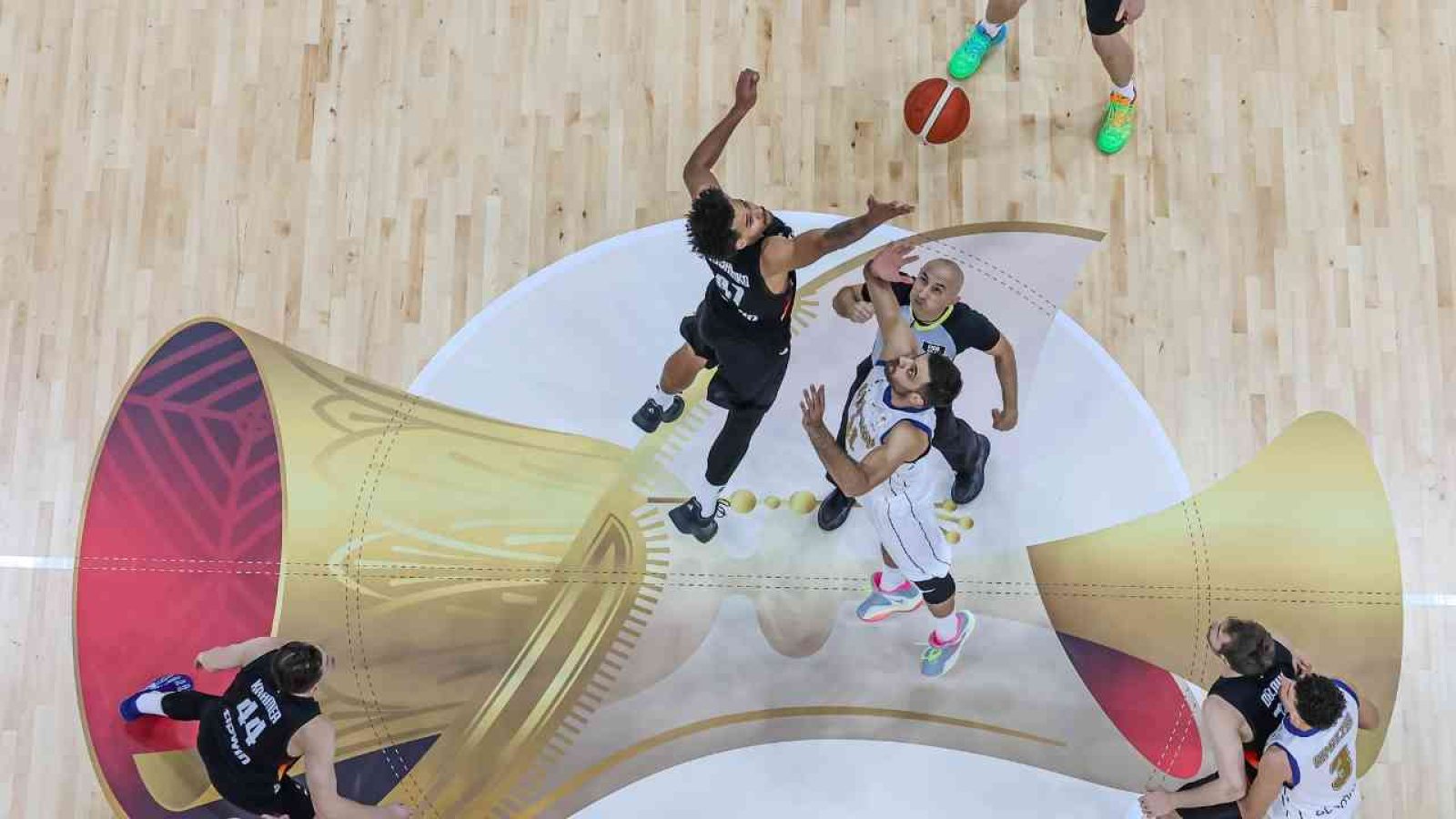 Basketballspiel mit Spielern, die beim Sprungball um den Ball kämpfen auf einem Holzboden.