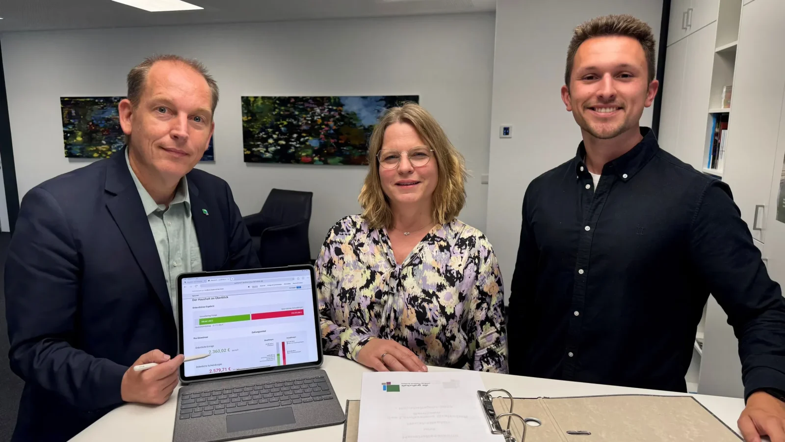 Der Grafschafter Haushaltsplan 2025 füllt einen ganzen Aktenordner. Eine Online-Visualisierung bietet schnellen Überblick: (v.l.) Frank Somberg, Erste Kreisrätin Sandra Cichon und Marcel Waldmann präsentieren das neue Tool.