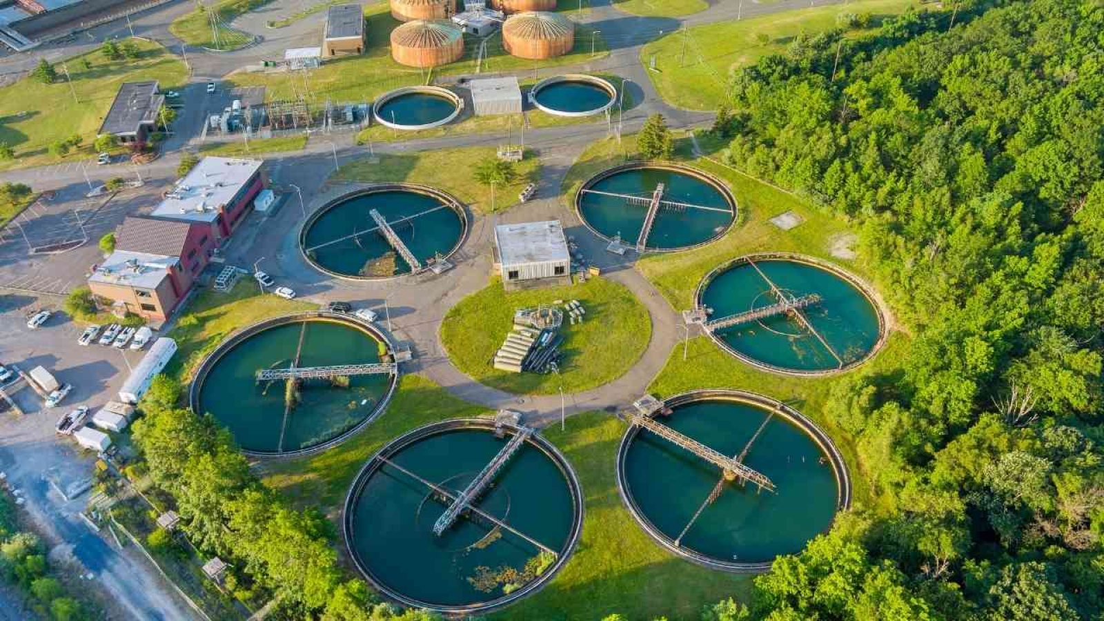 Kläranlage aus der Vogelperspektive: Sechs runde Becken umgeben von Grünflächen und Gebäuden.