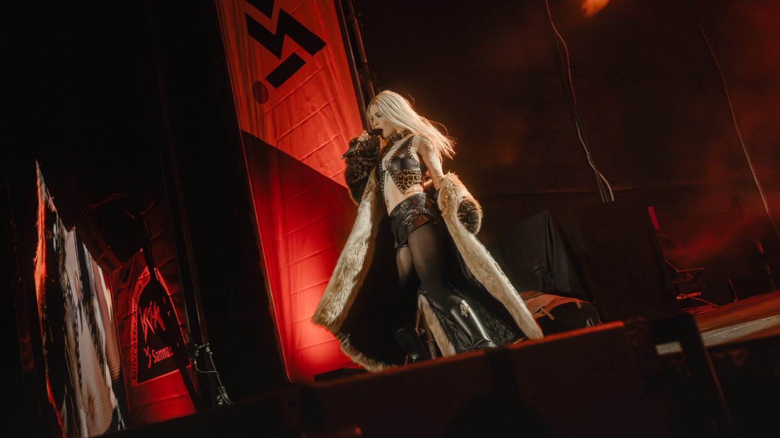 Künstlerin auf der Bühne mit langen blonden Haaren und einem auffälligen Outfit während eines Auftritts.