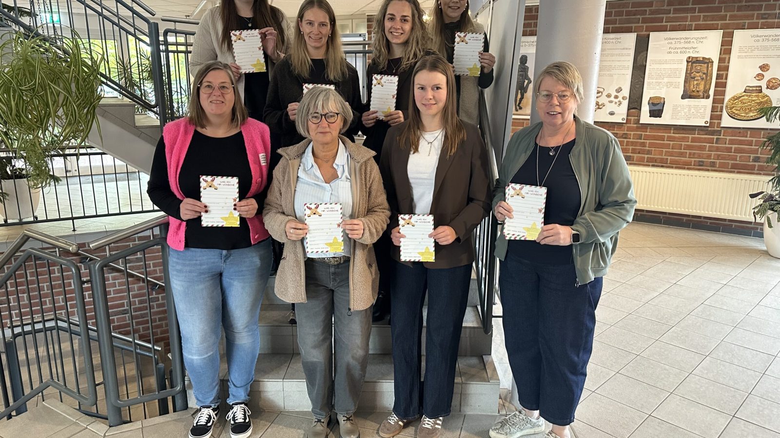 Acht Frauen stehen auf einer Treppe im Rathausfoyer und halten Wunschzettel in den Händen