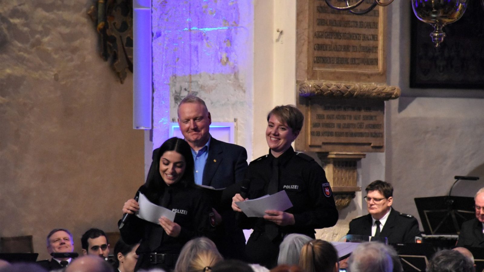 Zwei Studierende der Polizeiakademie Niedersachen richten einen besinnlichen Gruß an die Gäste - im Hintergrund Pastor Marcus Christ.
