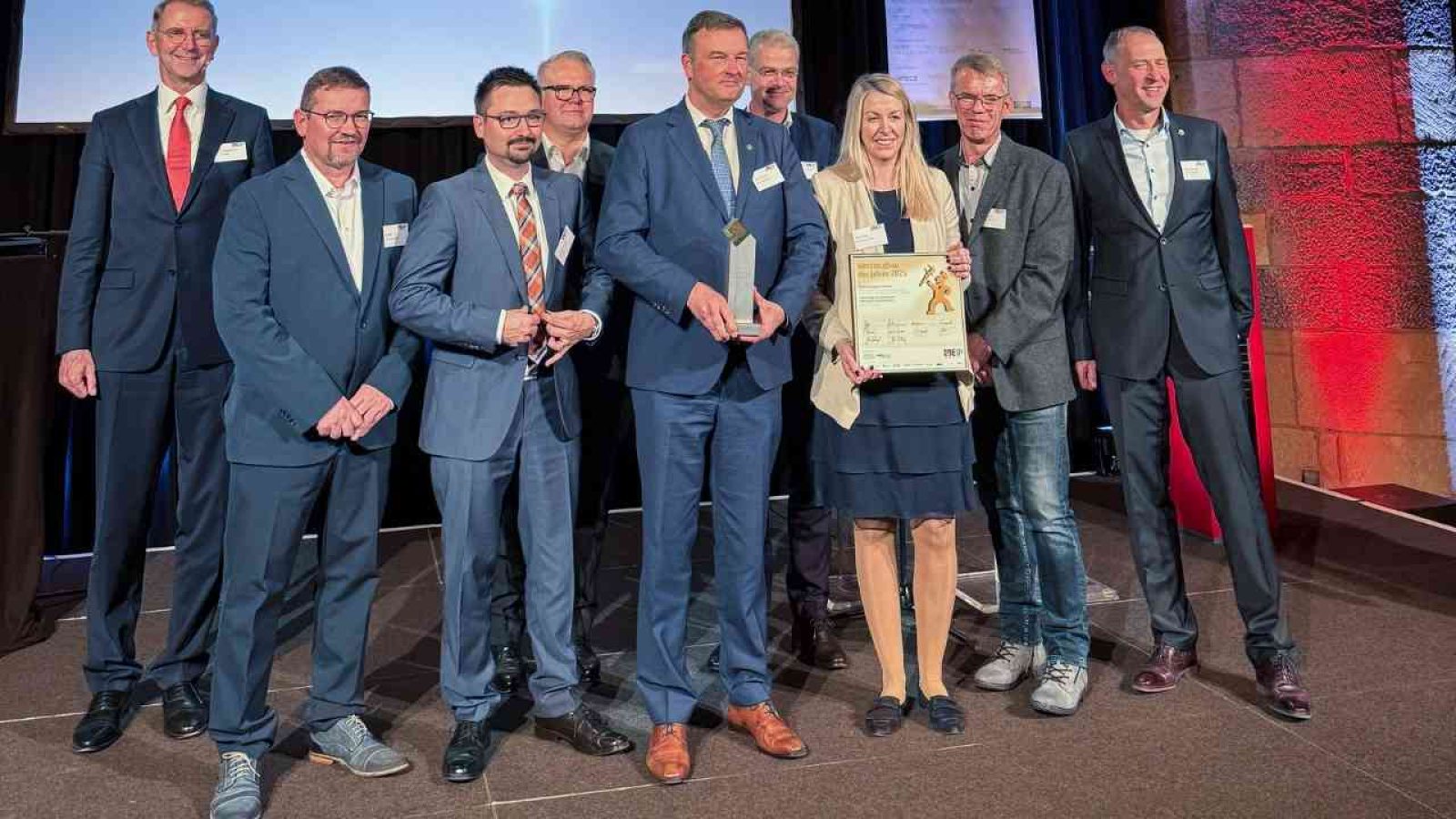 Gruppe von Personen, die bei einer Preisverleihung auf einer Bühne stehen und Auszeichnungen halten.