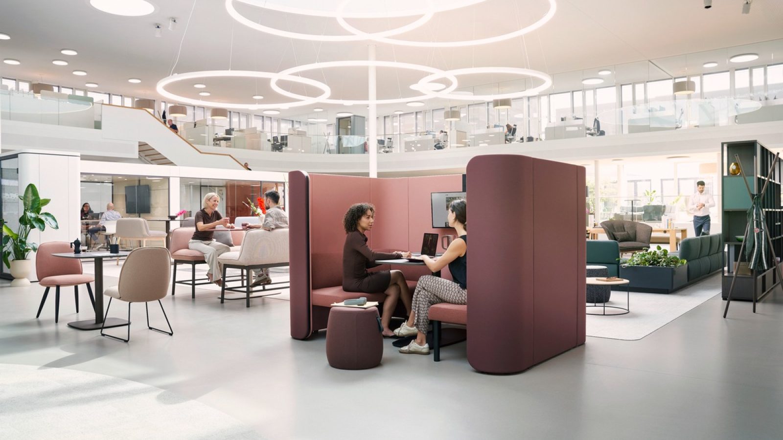 Moderne Büroumgebung mit Sitzgelegenheiten und Besprechungsbereichen für Mitarbeiter in einem offenen Raum.