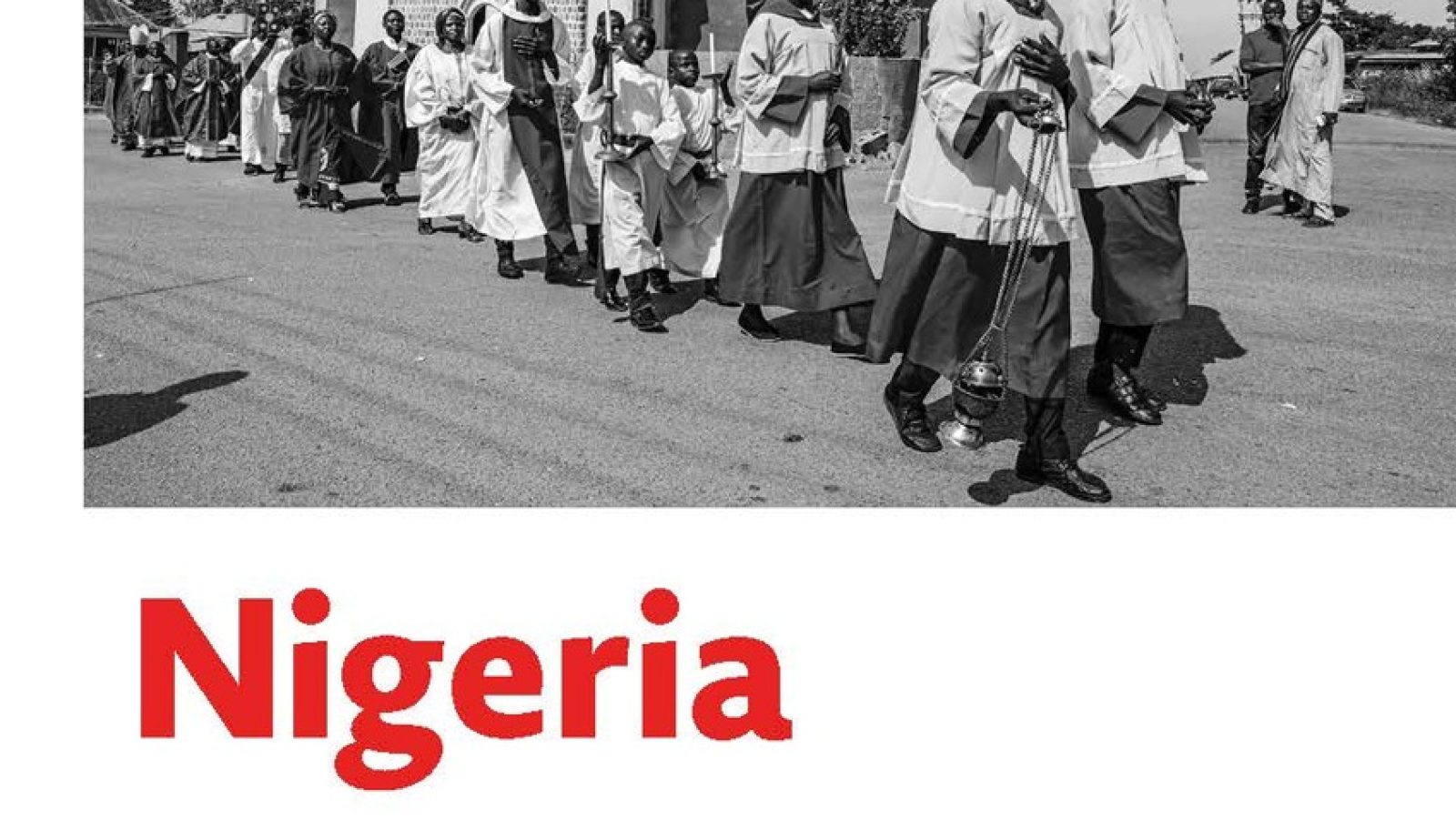 Schwarz-weiß Bild einer Prozession mit Menschen in traditionellen Gewändern vor einer Kirche in Nigeria.
