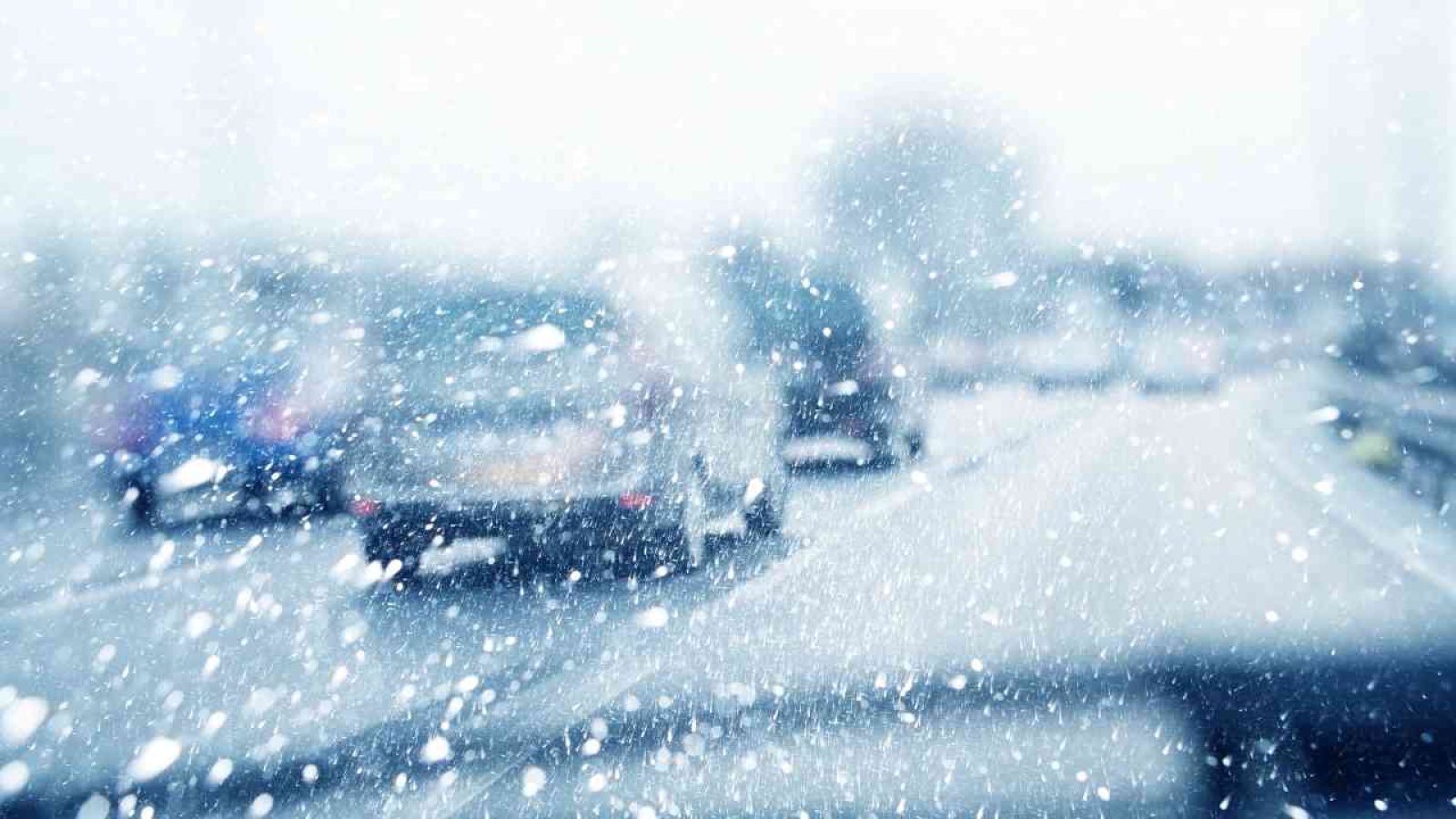 Autos auf einer verschneiten Straße während eines Schneesturms mit Sichtbehinderung.