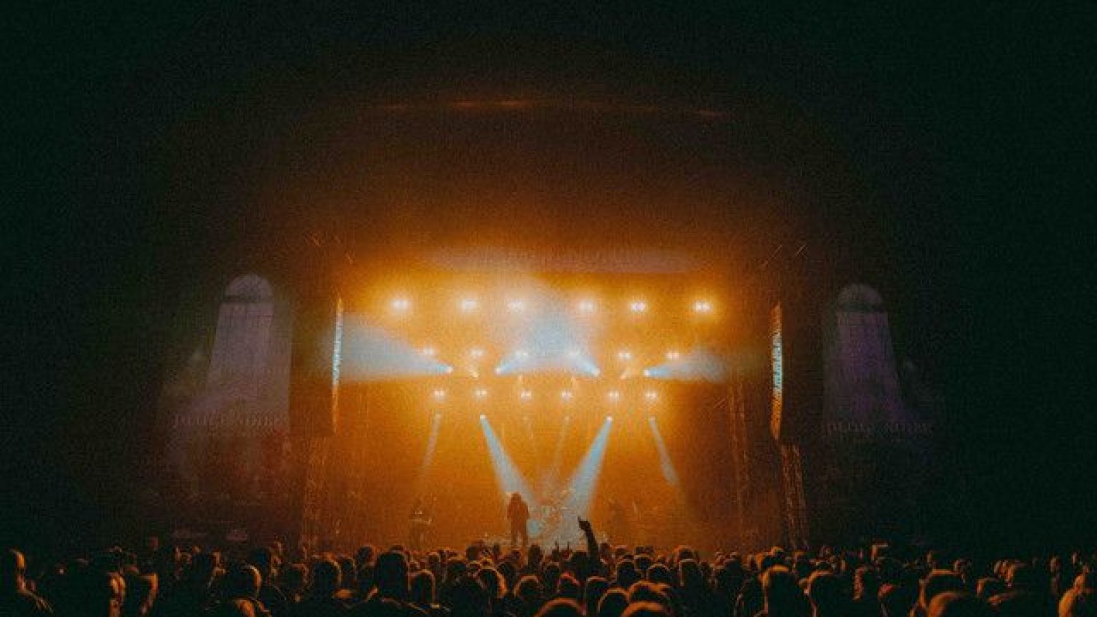 Bühne mit Lichtern und einer Menschenmenge während eines Musikfestivals.
