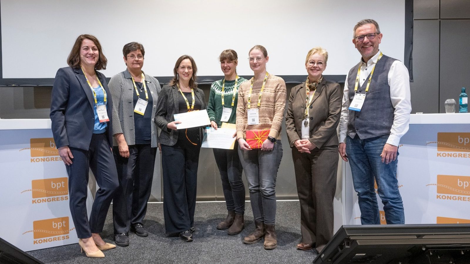 Gruppe von sieben Personen, die bei einer Preisverleihung in Frankfurt auf der Bühne stehen und Urkunden halten.