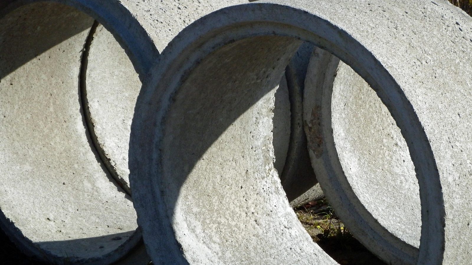 Drei zylindrische Betonrohre, die übereinander gestapelt sind und Schatten werfen.