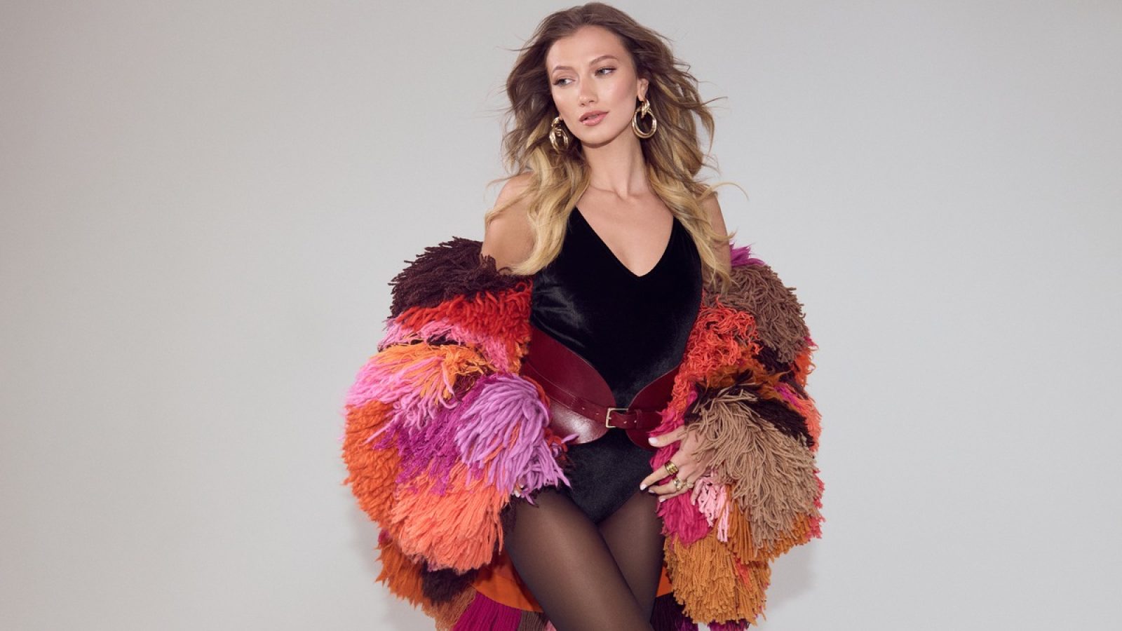 Model trägt einen bunten, flauschigen Mantel mit verschiedenen Farbtönen und einem schwarzen Body.