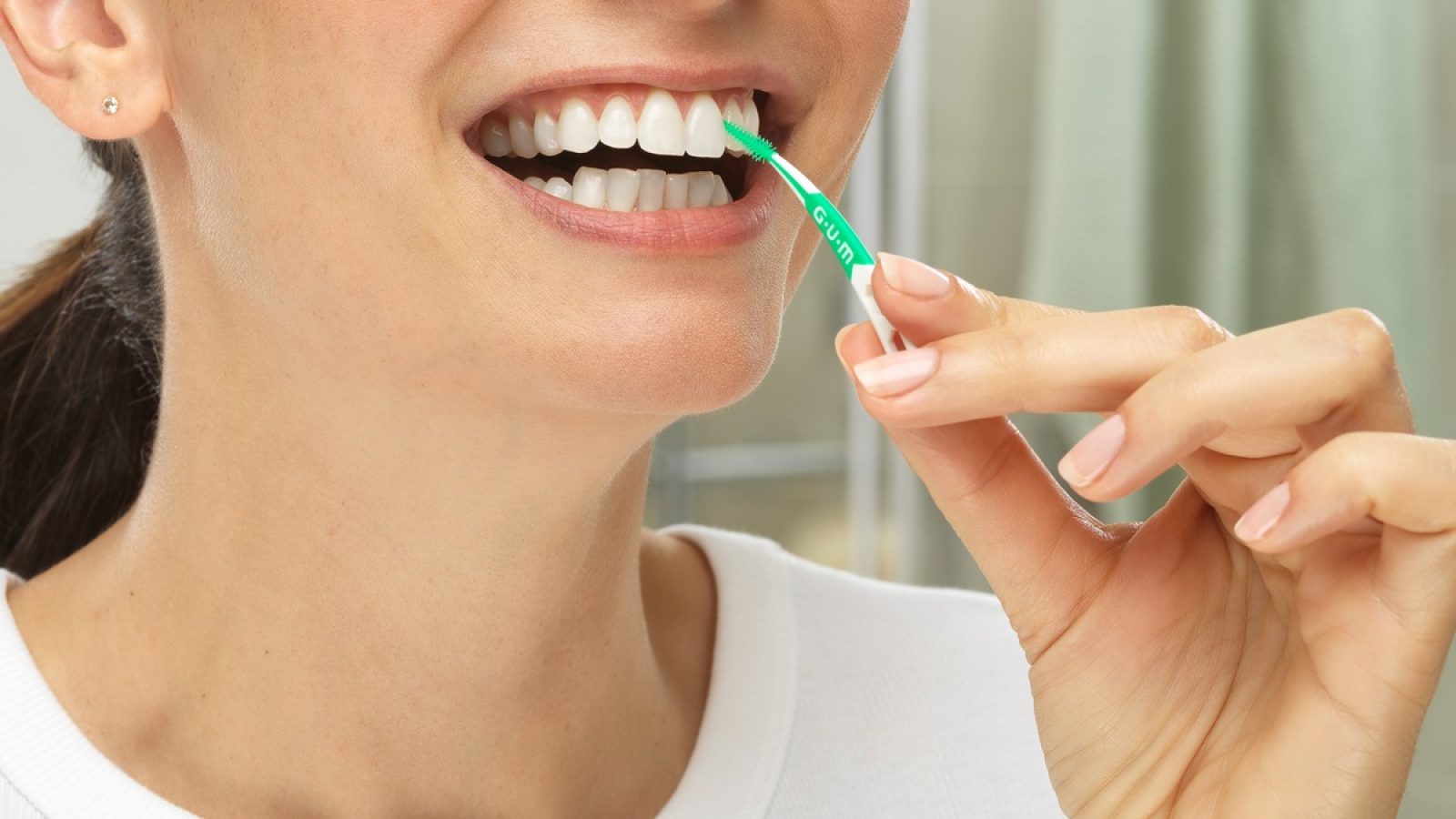 Nahaufnahme einer lächelnden Frau bei der Zahnzwischenraumpflege im Badezimmer. / Weiterer Text über ots und www.presseportal.de/nr/178708 / Die Verwendung dieses Bildes für redaktionelle Zwecke ist unter Beachtung aller mitgeteilten Nutzungsbedingungen zulässig und dann auch honorarfrei. Veröffentlichung ausschließlich mit Bildrechte-Hinweis.